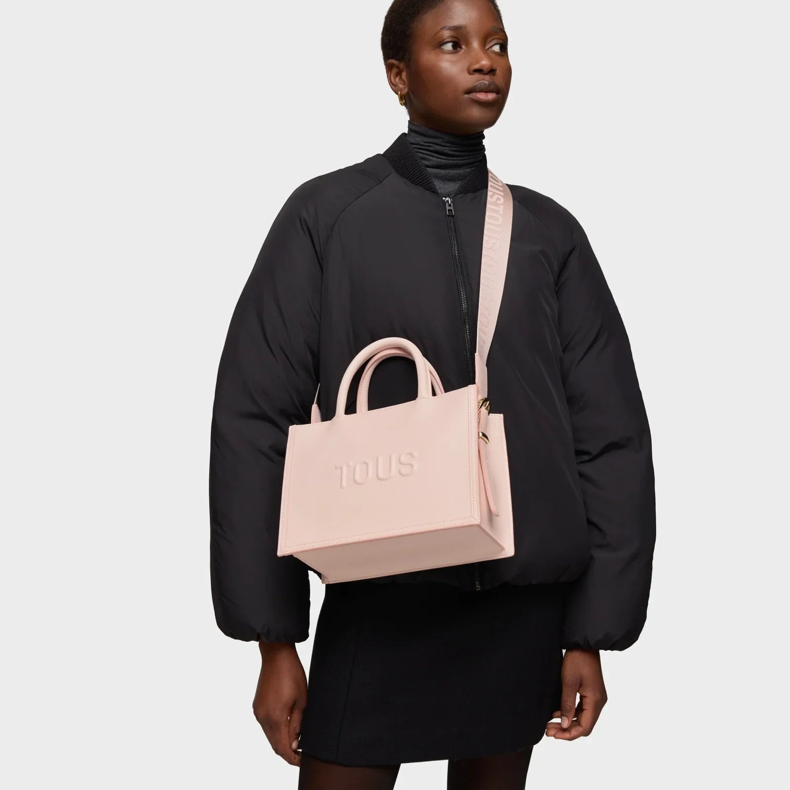 אישה עם מעיל שחור ותיק ורוד של TOUS, אופנה יוקרתית ב-CHOZEN