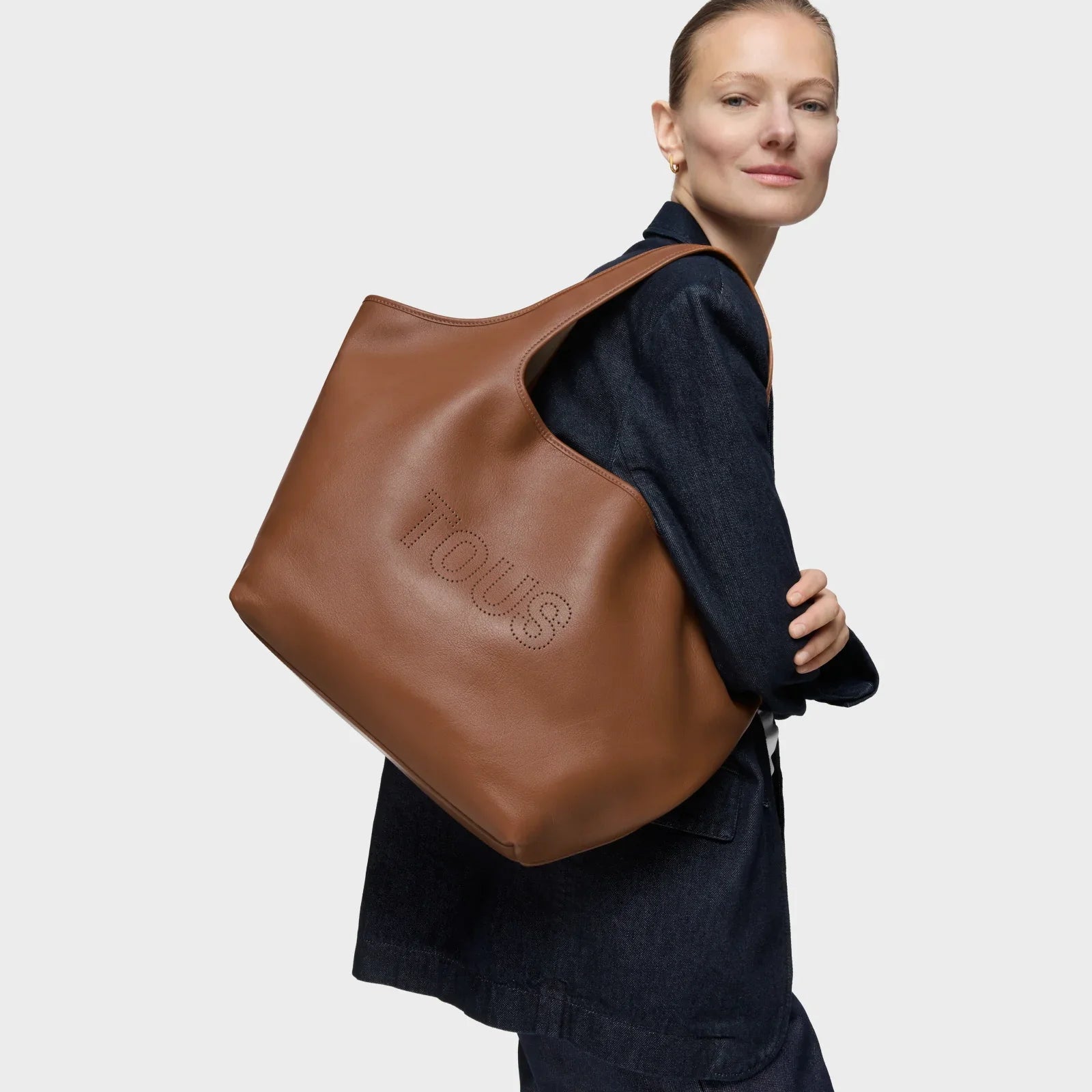 אישה לובשת תיק עור חום ממותג TOUS, אופנה יוקרתית CHOZEN קבוצת אלפא