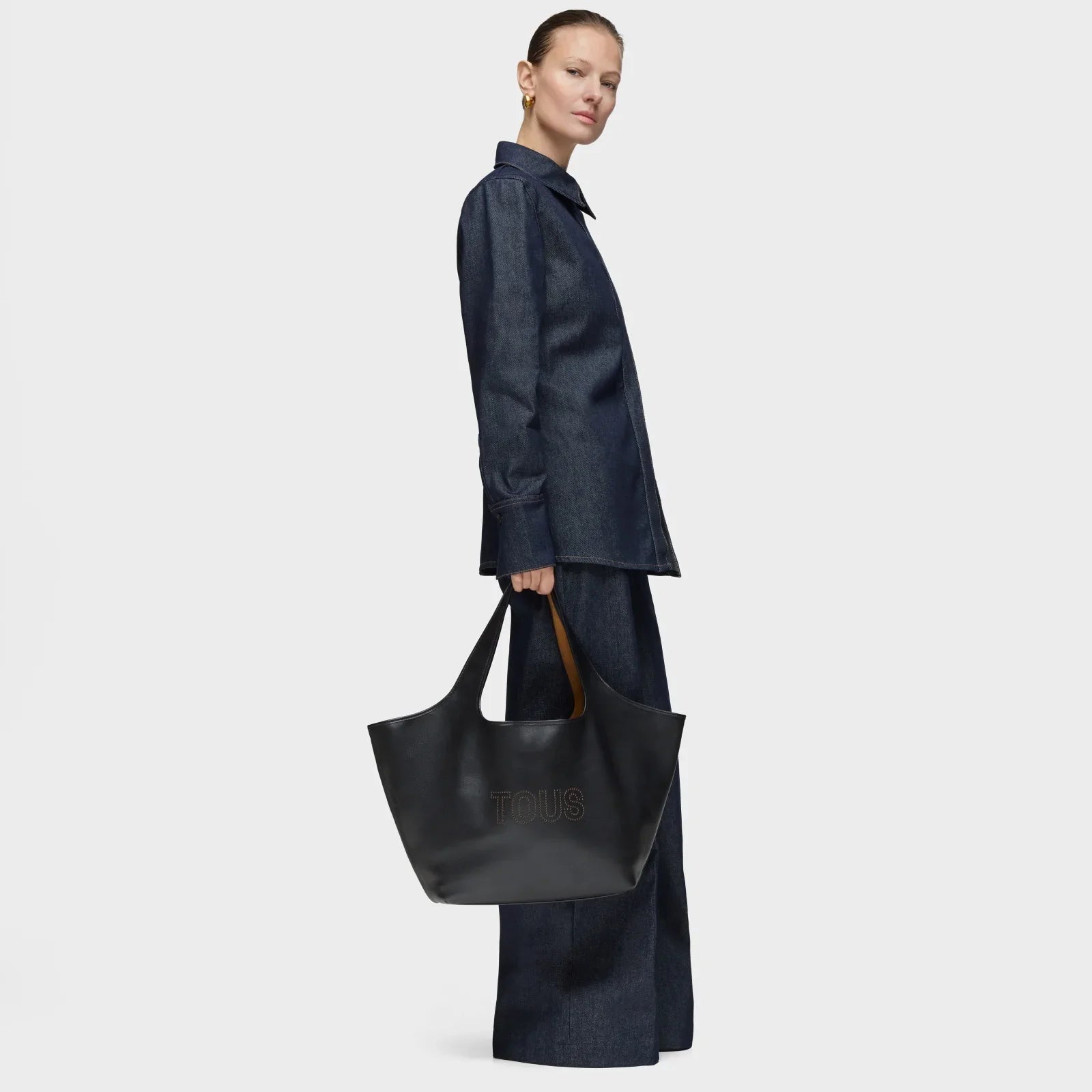דוגמנית עם חליפת ג'ינס כהה מחזיקה תיק עור שחור TOUS, אופנה יוקרתית CHOZEN קבוצת אלפא