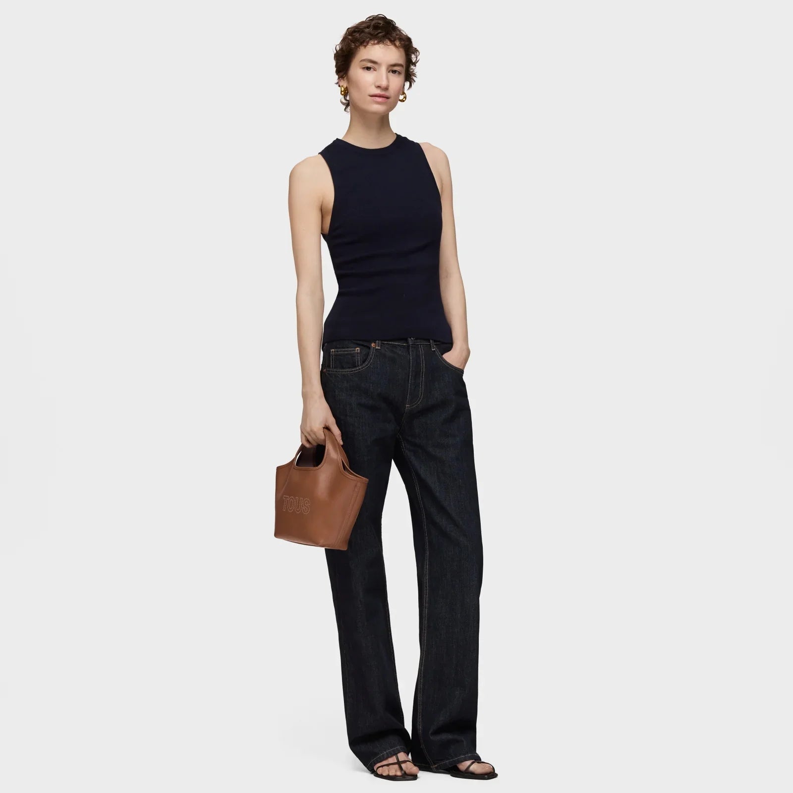 אישה לובשת גופיה שחורה ומכנסי ג'ינס כהים מחזיקה תיק חום, CHOZEN מותגים מובילים