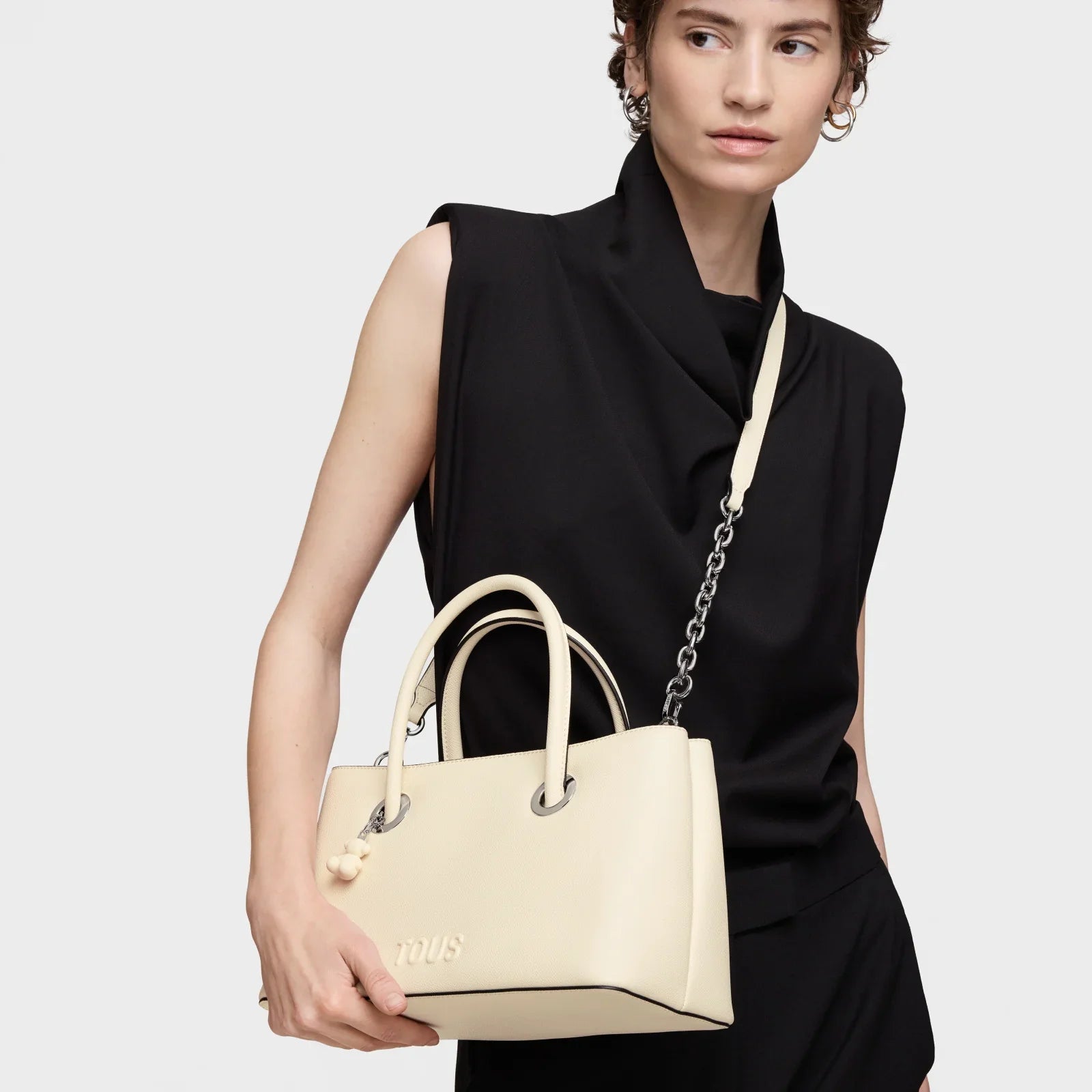 אישה עם תיק יד קרם אלגנטי מבית TOUS, לבושה בבגד שחור, צילום סטודיו ל-CHOZEN