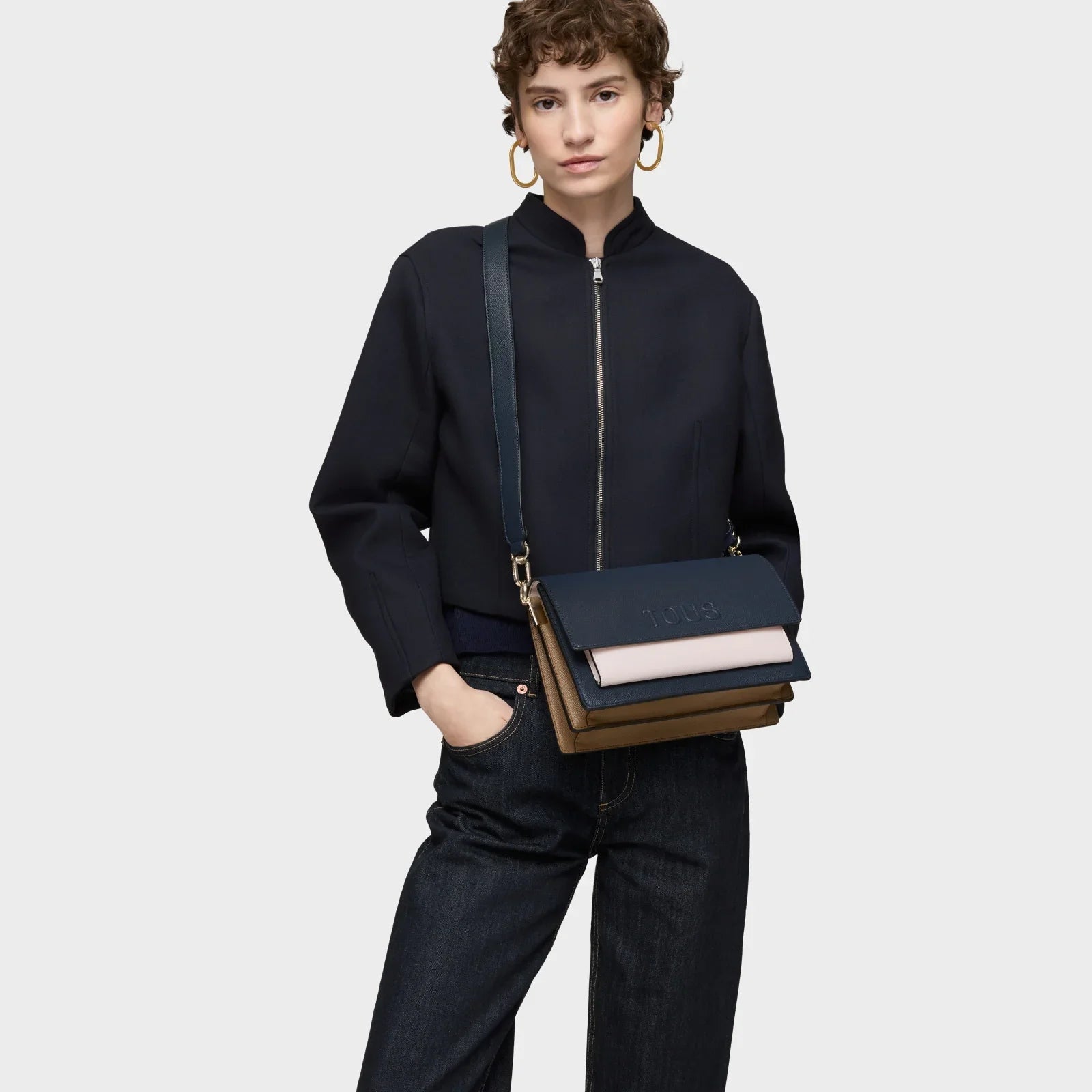 אשה עם תיק צד אופנתי בצבע כחול ומעיל כהה, מותג CHOZEN, צילום רקע לבן אופנתי