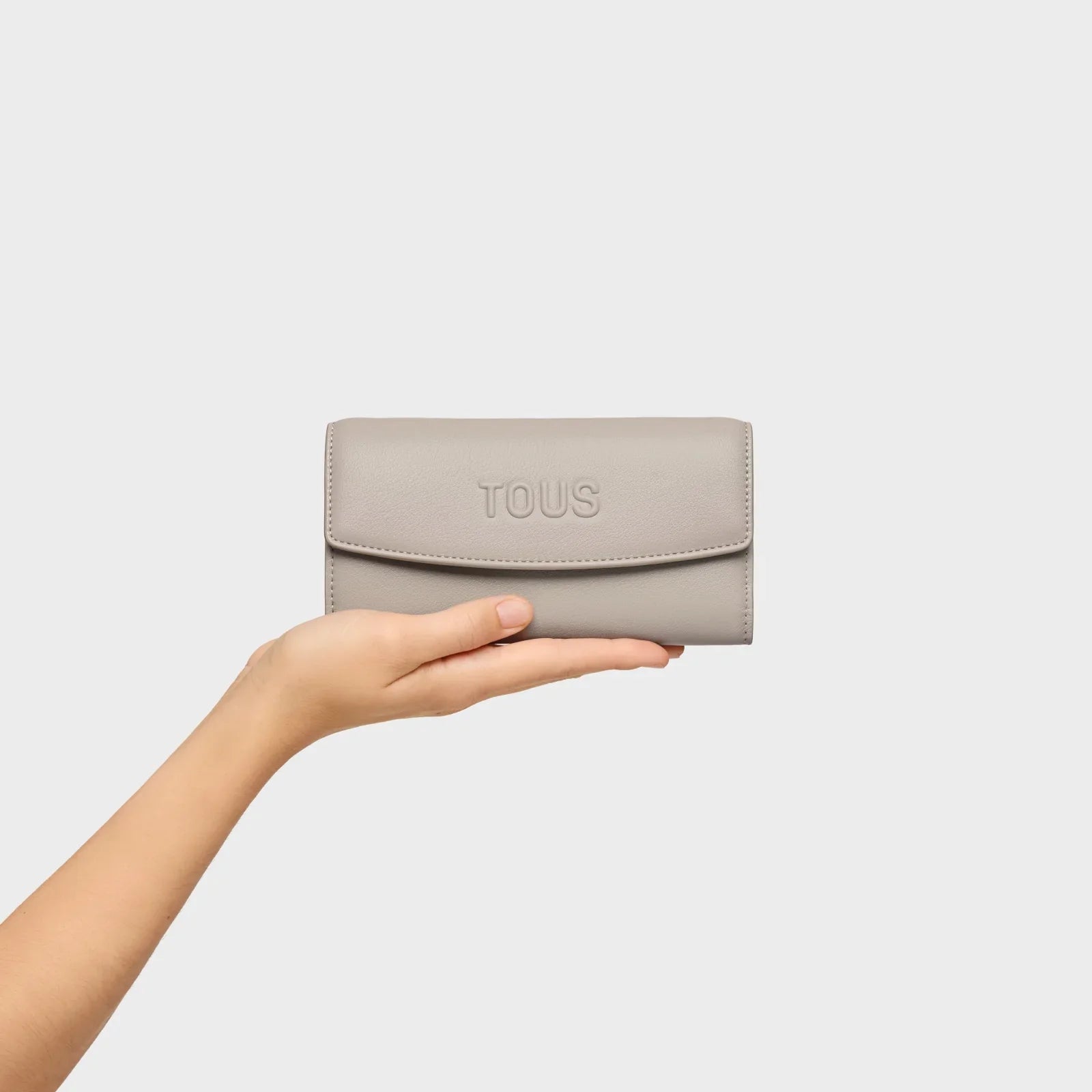 ארנק עור אפור TOUS על כף יד, מותג בינלאומי מקבוצת אלפא CHOZEN