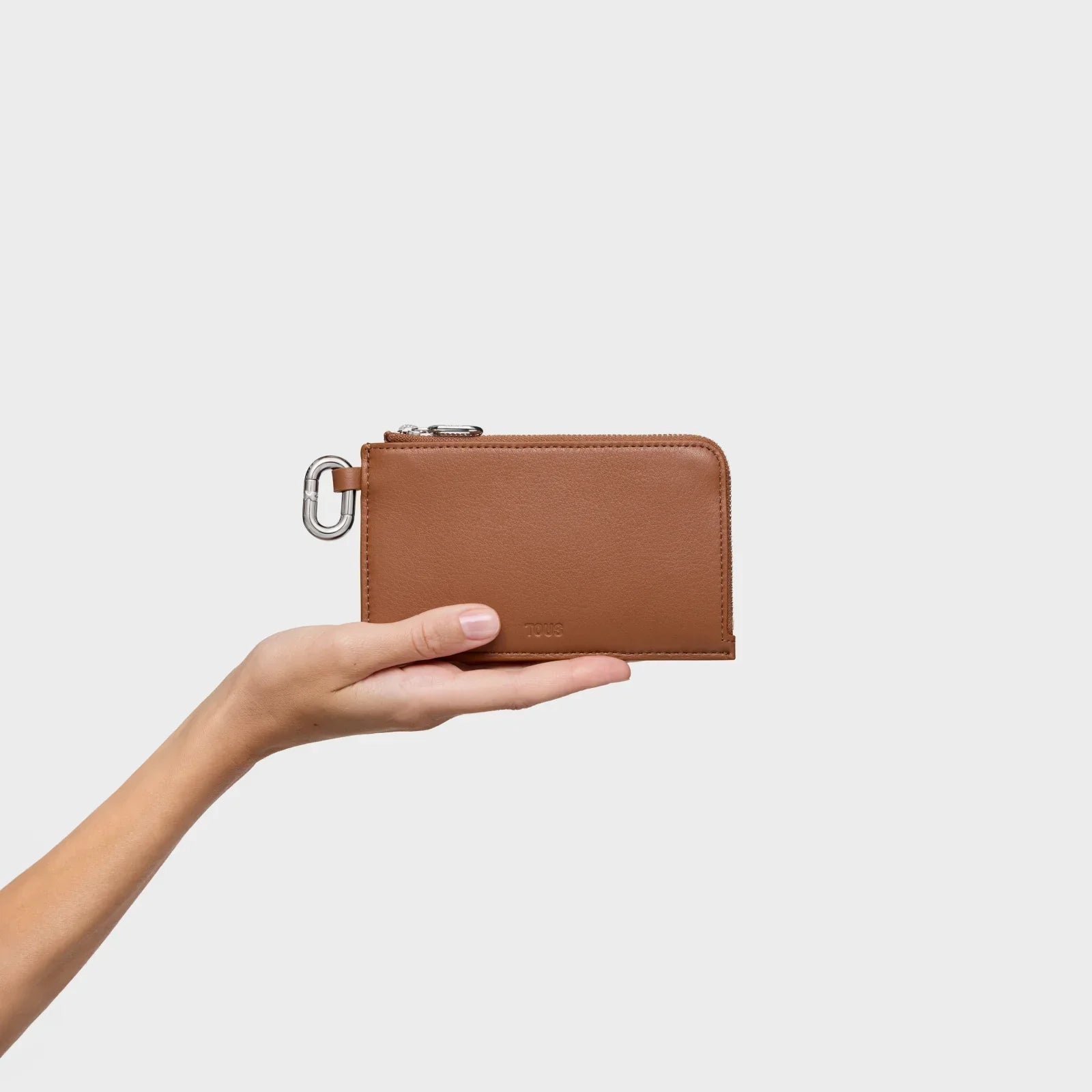 ארנק עור חום אלגנטי של מותג יוקרתי מוצג על כף יד, צילום מוצר לחנות CHOZEN