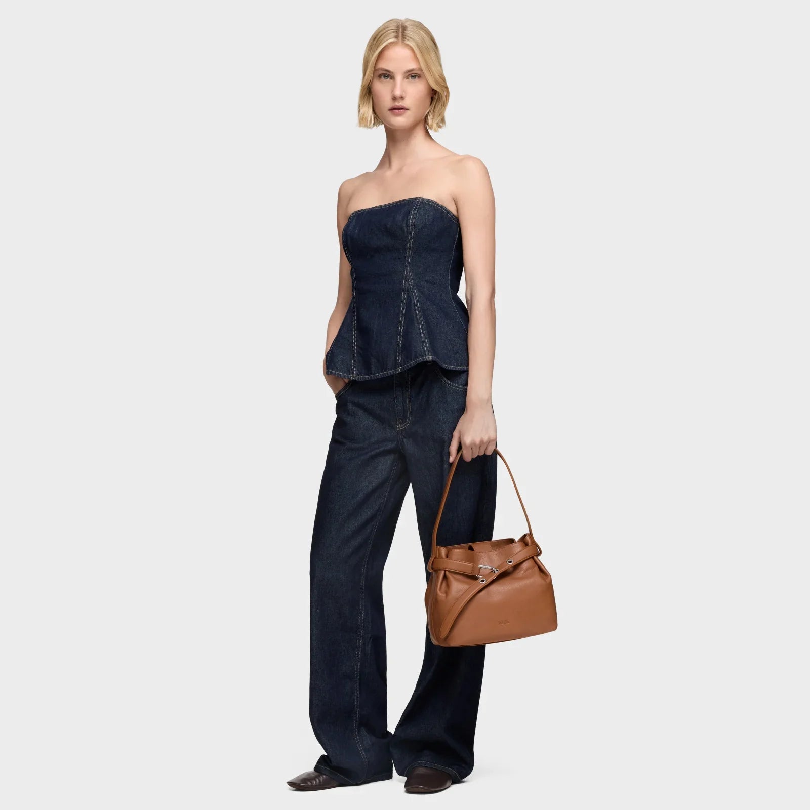 אישה לובשת סט ג'ינס אופנתי ומחזיקה תיק חום, צילום קטלוג אופנה מבית CHOZEN