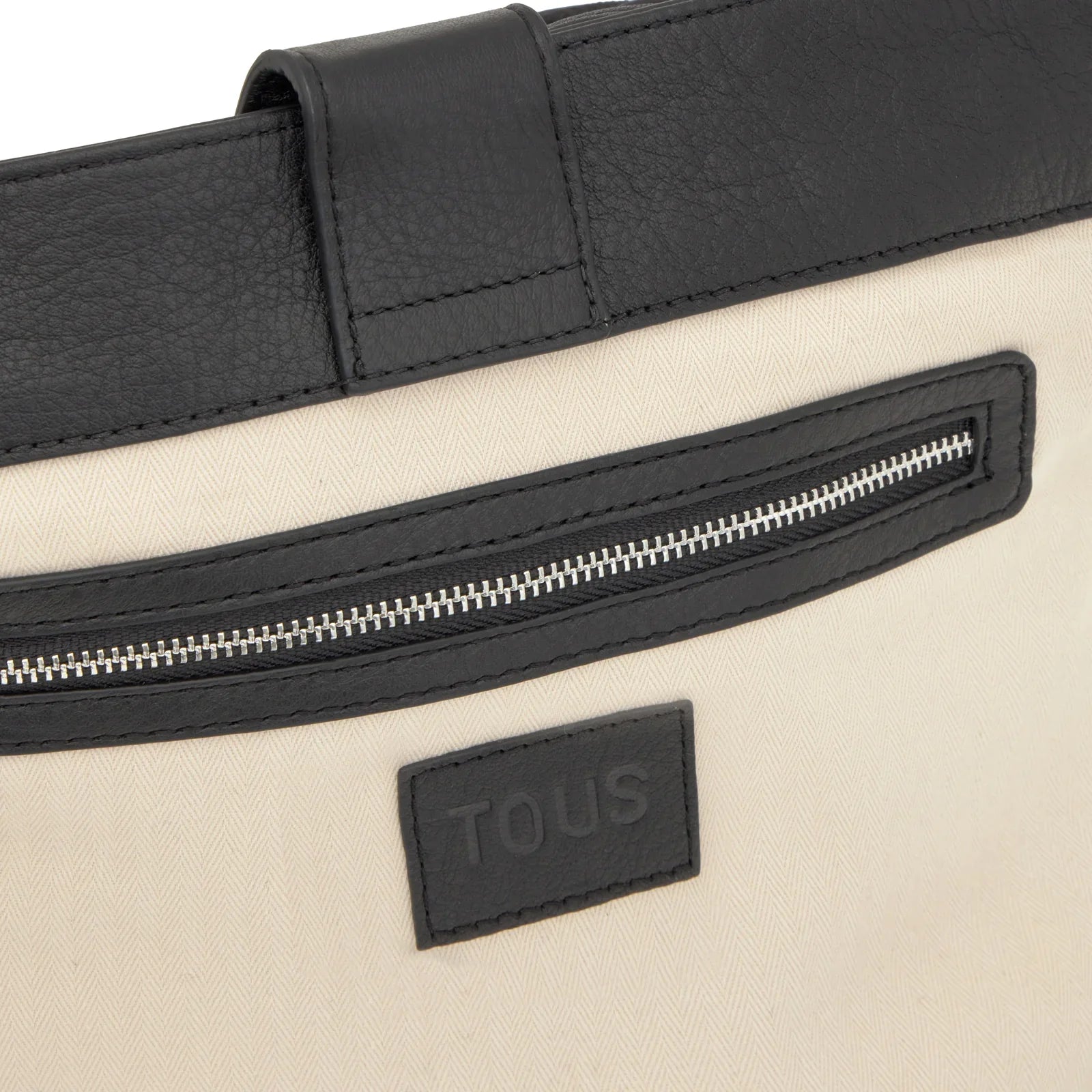 תקריב תיק TOUS מבד בז' עם קישוטי עור שחור, רוכסן ותווית לוגו, קולקציית מותגים ב-CHOZEN