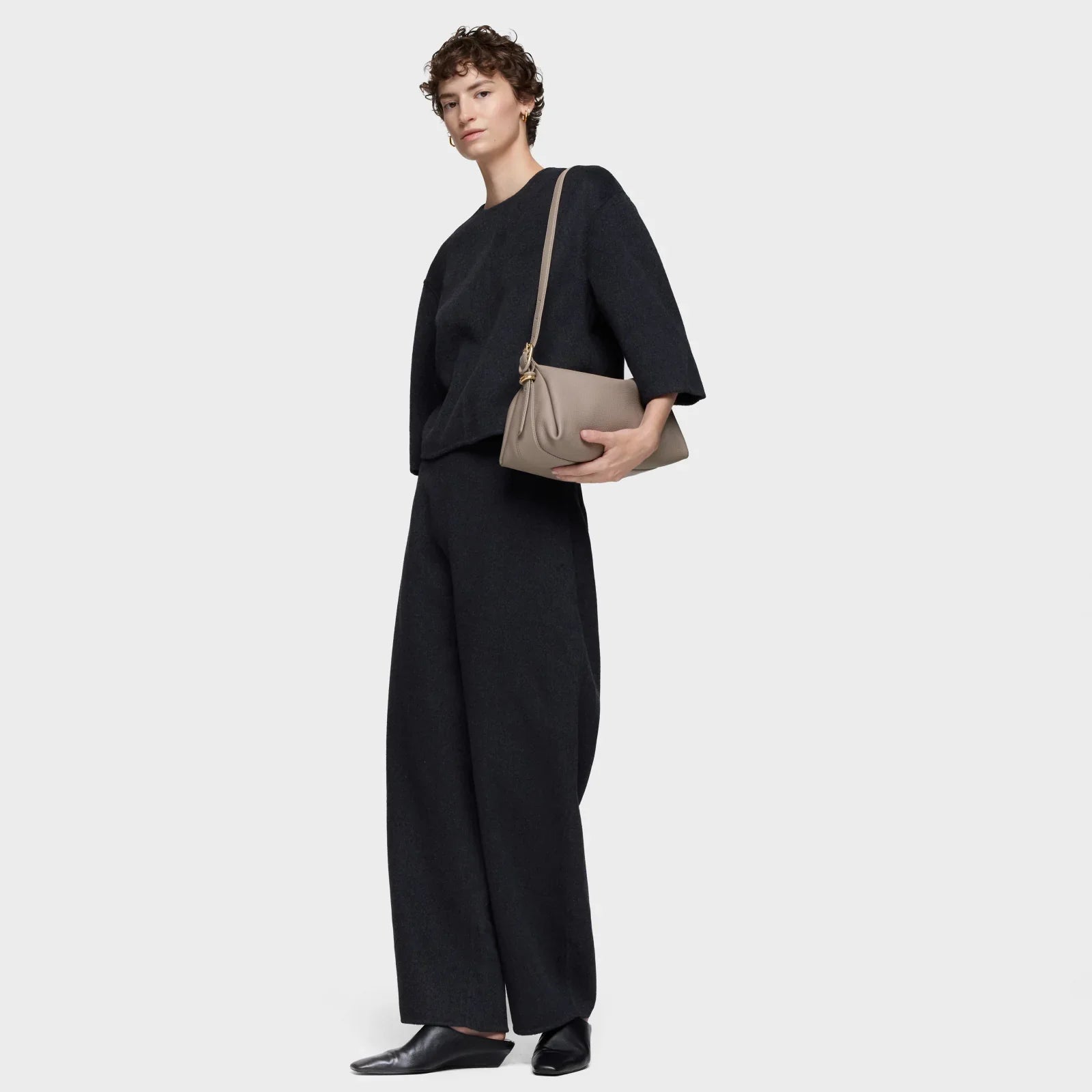 אישה מדגמנת סט חליפה שחורה עם תיק צד אופנתי, צילום אופנה לקבוצת אלפא CHOZEN