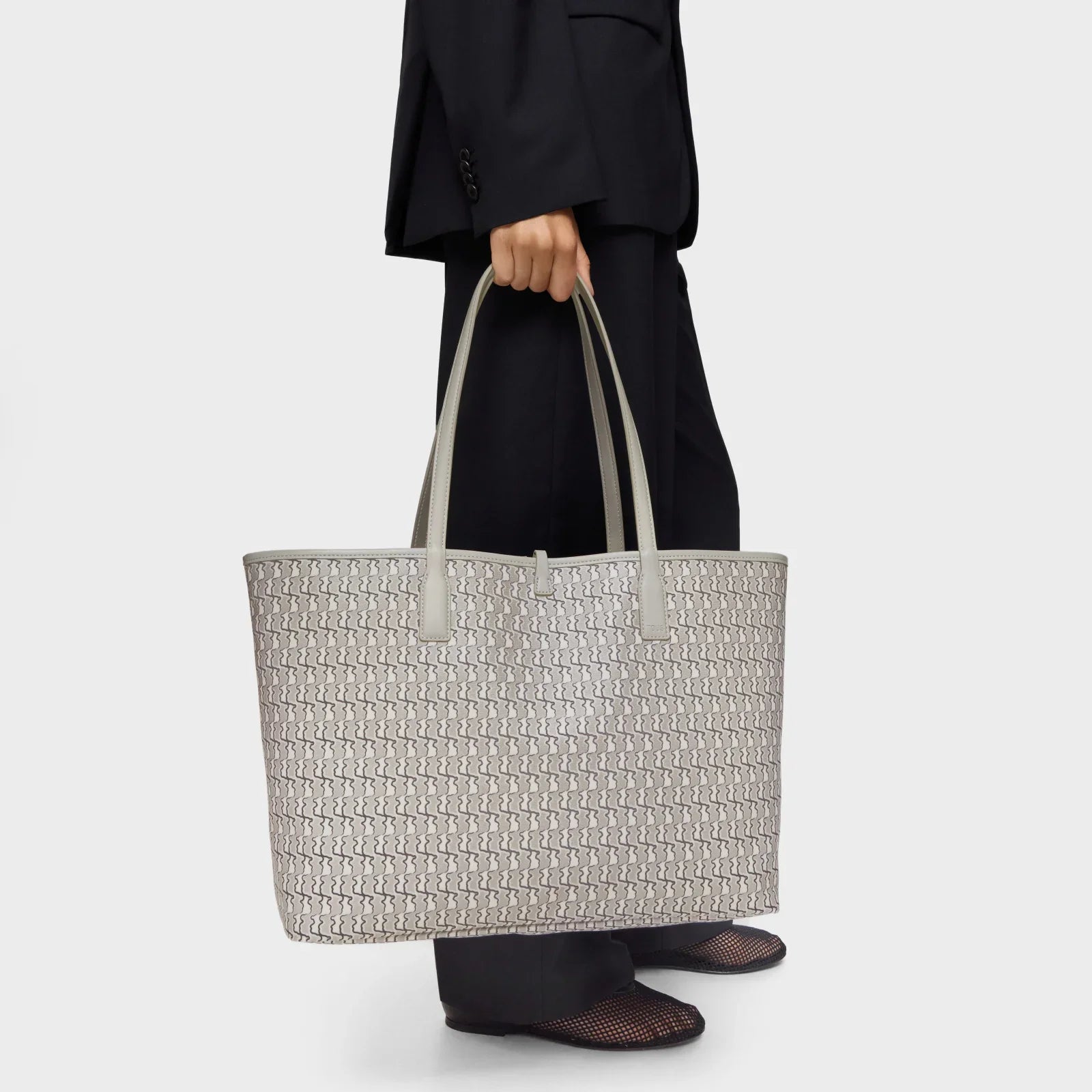 תיק יד גדול בעיצוב יוקרתי עם דוגמה גיאומטרית, נישא על ידי דוגמן בלבוש אלגנטי, CHOZEN