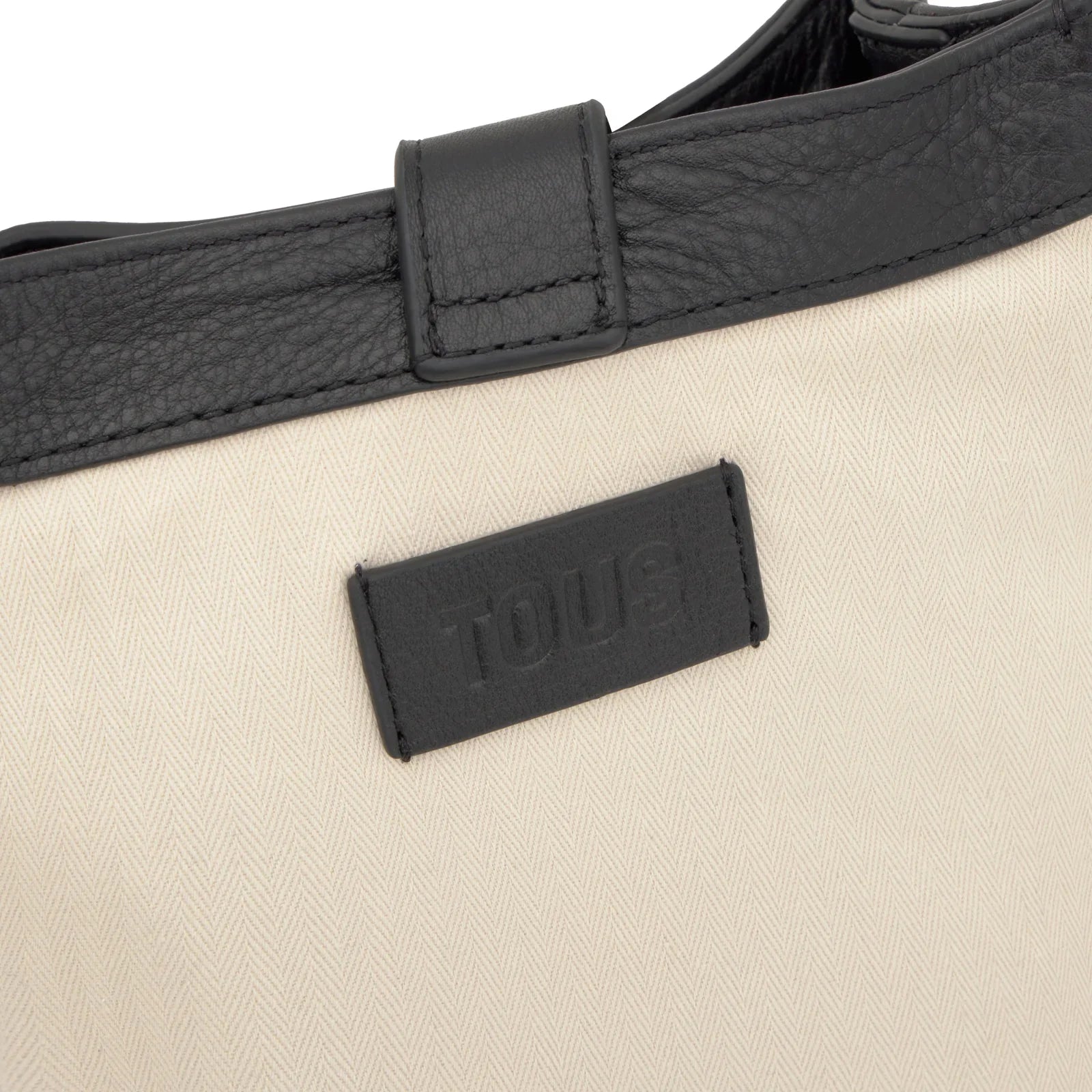 פרט תיק בד בז׳ עם דוגמת זיגזג ותווית עור שחורה של TOUS, עיצוב יוקרתי מבית CHOZEN