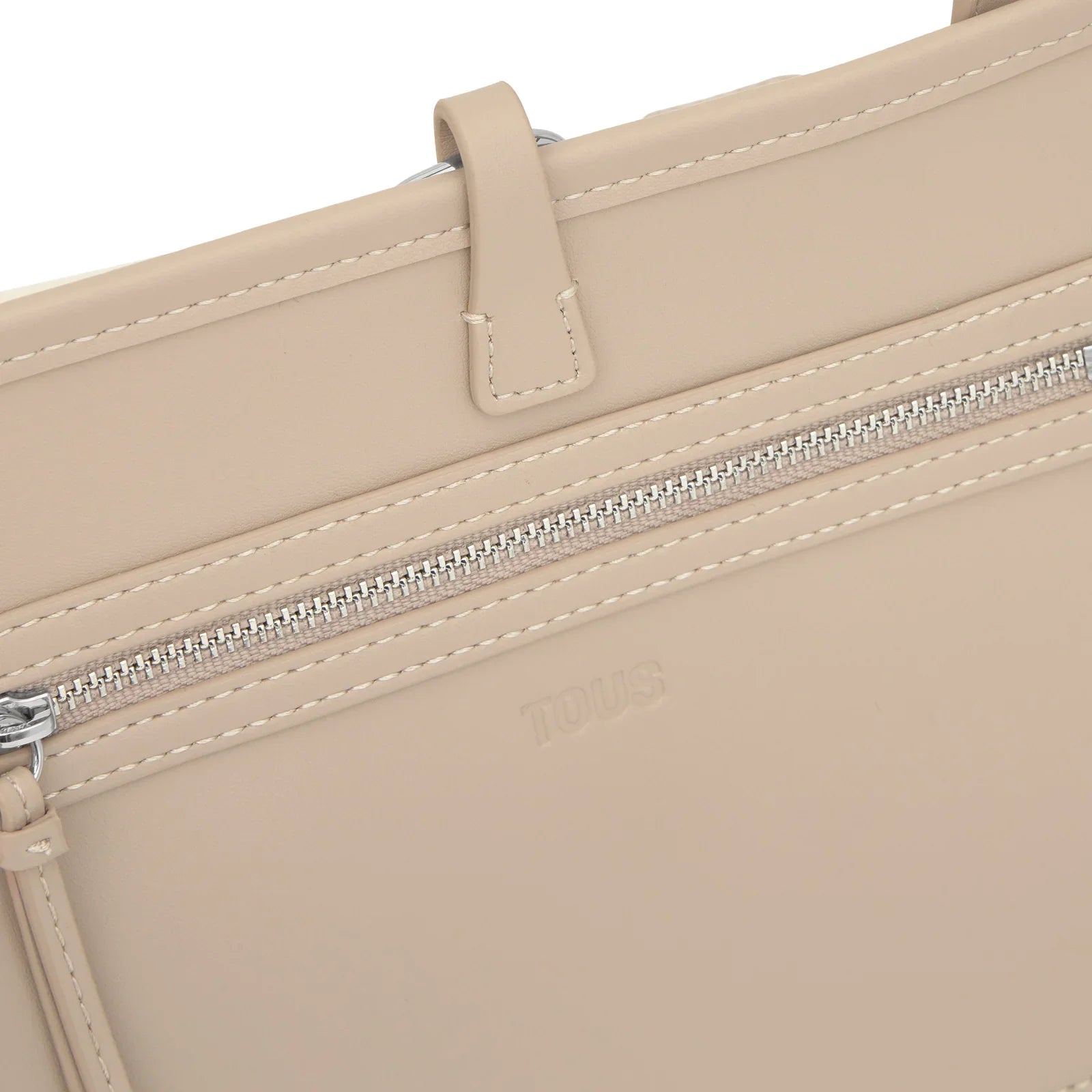 תקריב של תיק בז' עם רוכסן ולוגו TOUS, מותגים יוקרתיים ב-CHOZEN