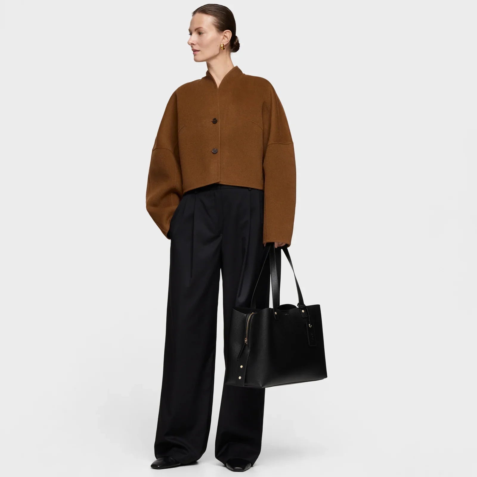 אישה עם ז'קט חום, מכנסיים שחורים ותיק יד, אופנה יוקרתית CHOZEN