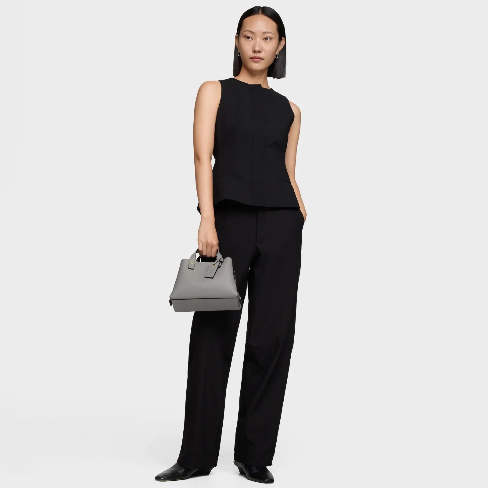 אישה לובשת חליפה שחורה אלגנטית ואוחזת תיק יד אפור, צילום לקטלוג מותגים מובילים מבית CHOZEN