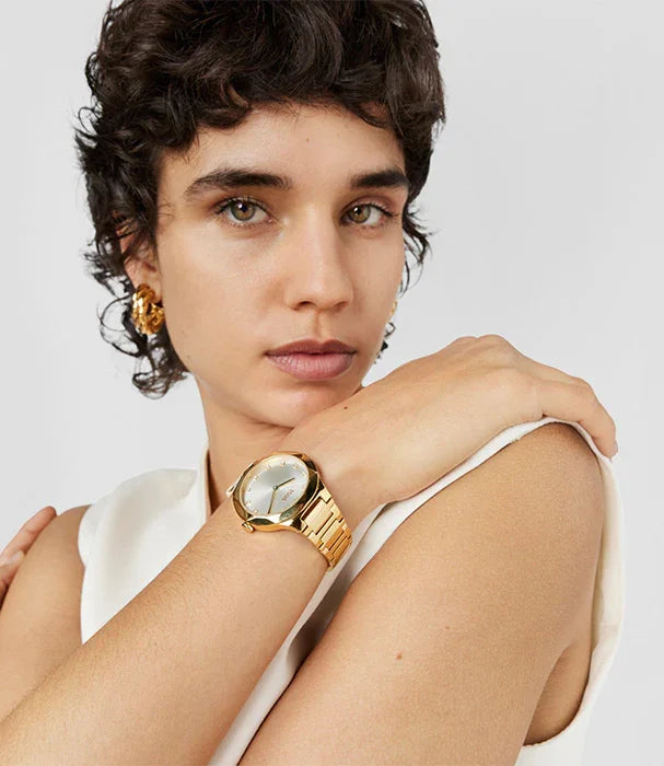אישה עם שיער קצר עונדת שעון יד זהב ועגילי זהב, צילום אופנה באתר CHOZEN