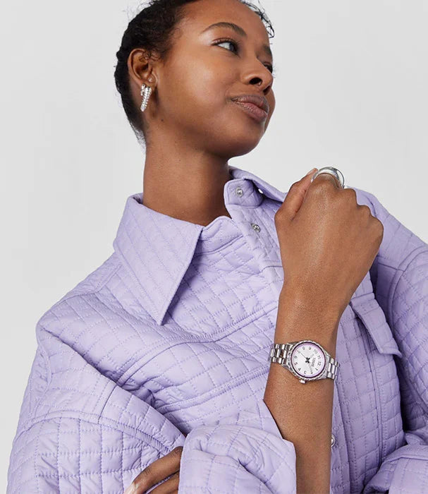 אישה עונדת שעון יוקרתי עם רצועת מתכת, חולצת סגול בהירה, מבית CHOZEN מותגים מובילים