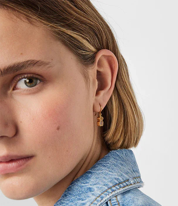 דוגמנית עם עגילי זהב עדינים, שיער קצר וז'קט ג'ינס, מבית CHOZEN