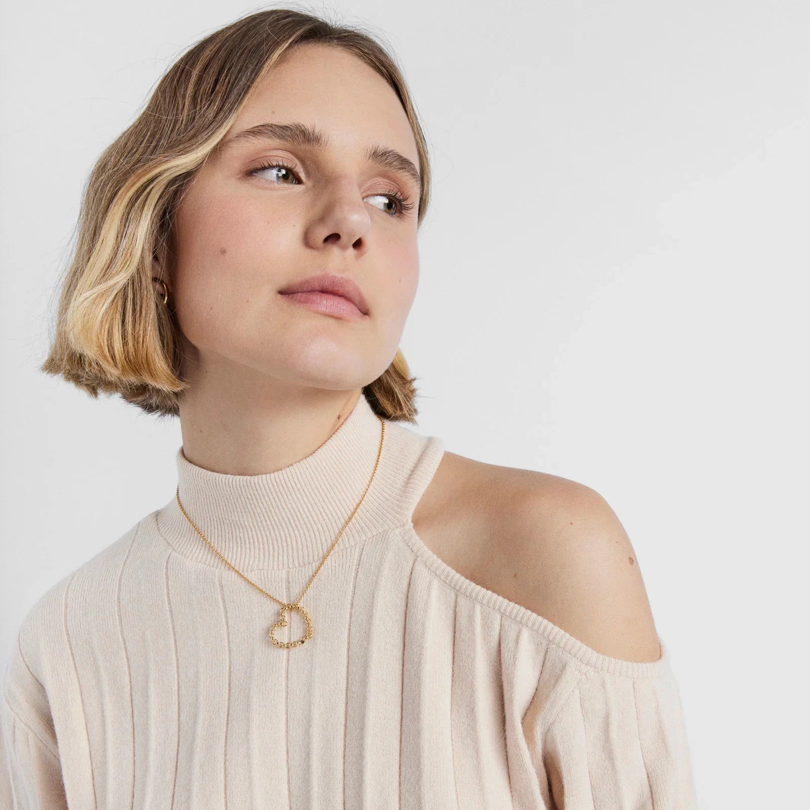 אישה עם סוודר בז׳ וצווארון גולף, שרשרת זהב מעוצבת, צילום אופנה CHOZEN