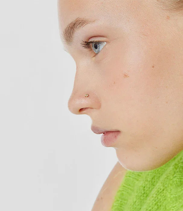 פרופיל של אישה עם פירסינג זהב באף, לבושה בגופיה ירוקה, CHOZEN מותגים מובילים