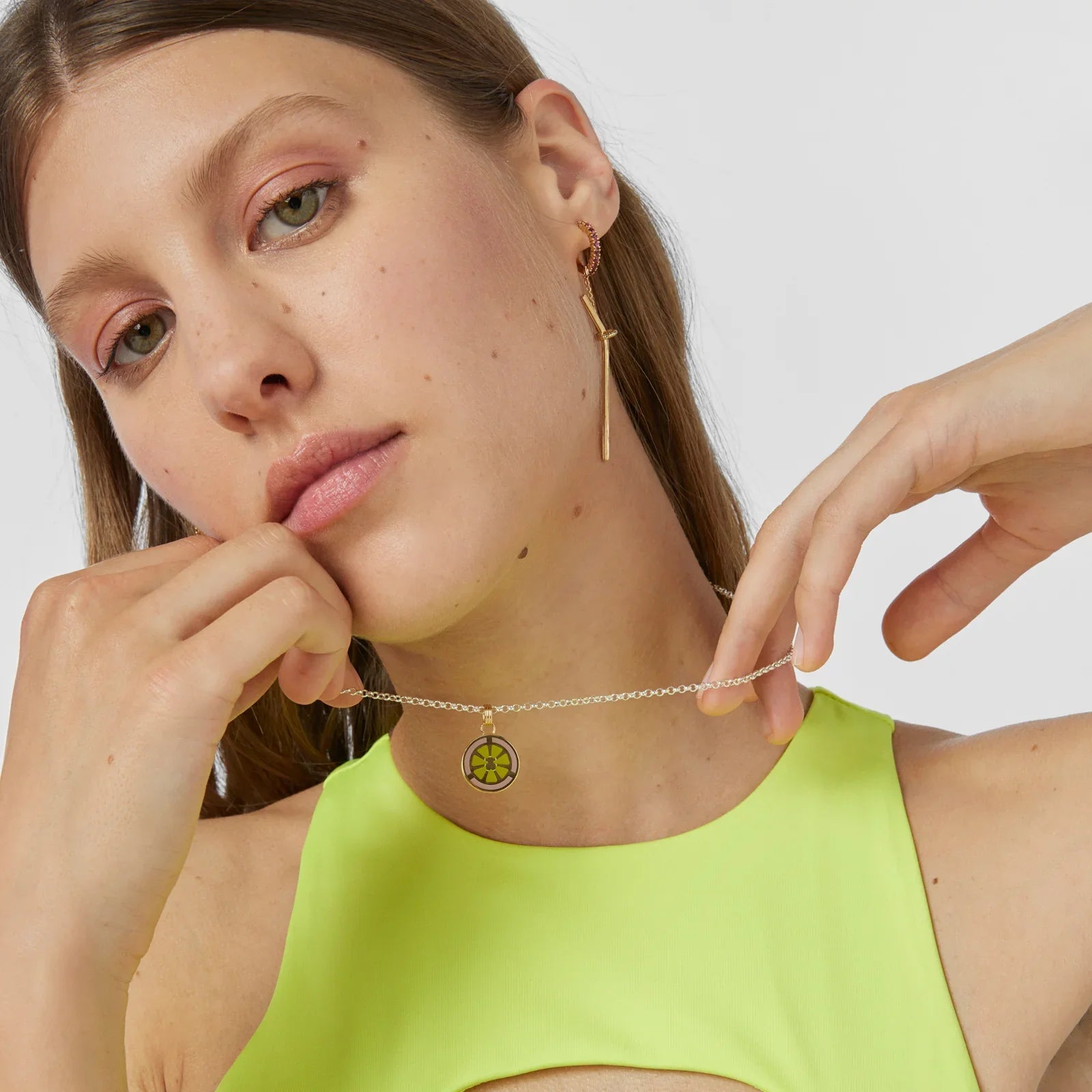 אישה דוגמנית עם שרשרת תליון זהב ועגיל, לובשת טופ ניאון, צילום סטודיו של מותג אופנה CHOZEN