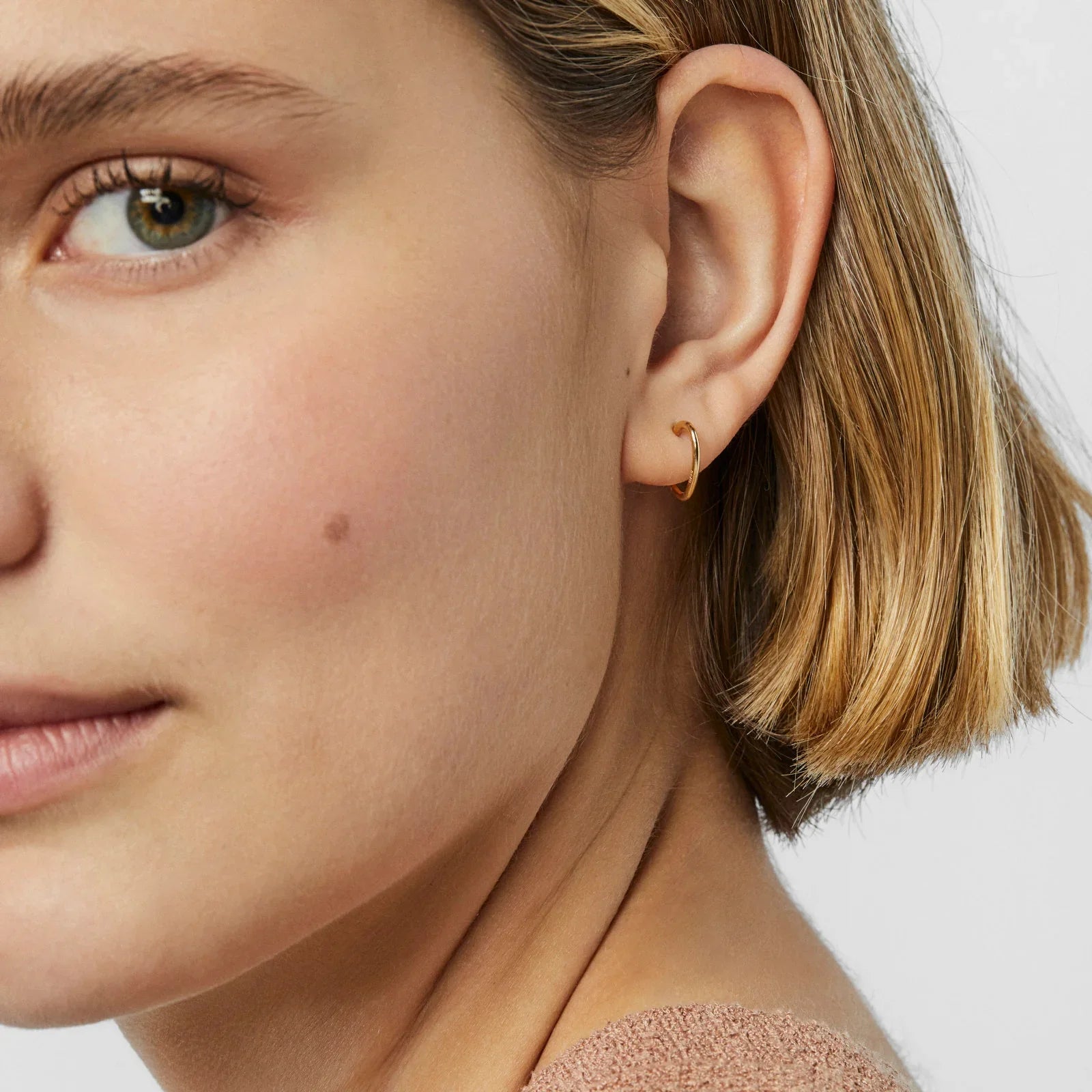 אישה עונדת עגיל חישוק זהב קטן, תקריב על האוזן, CHOZEN תכשיטים יוקרתיים