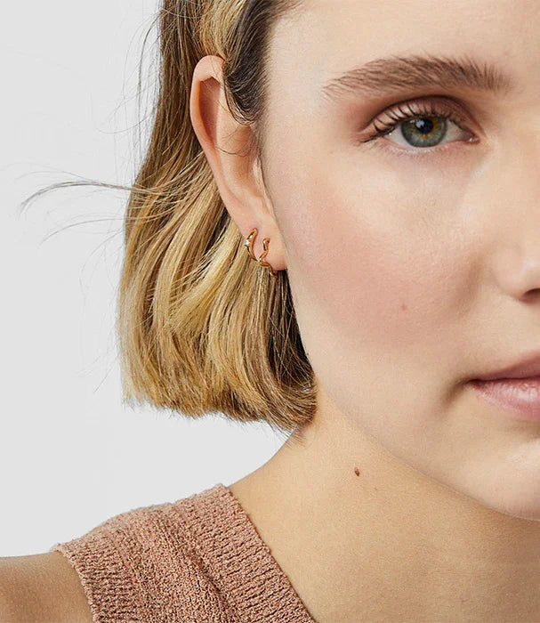 דוגמנית עם שיער בלונדיני קצר עונדת עגילי זהב, תקריב על הפנים, CHOZEN מותגים מובילים