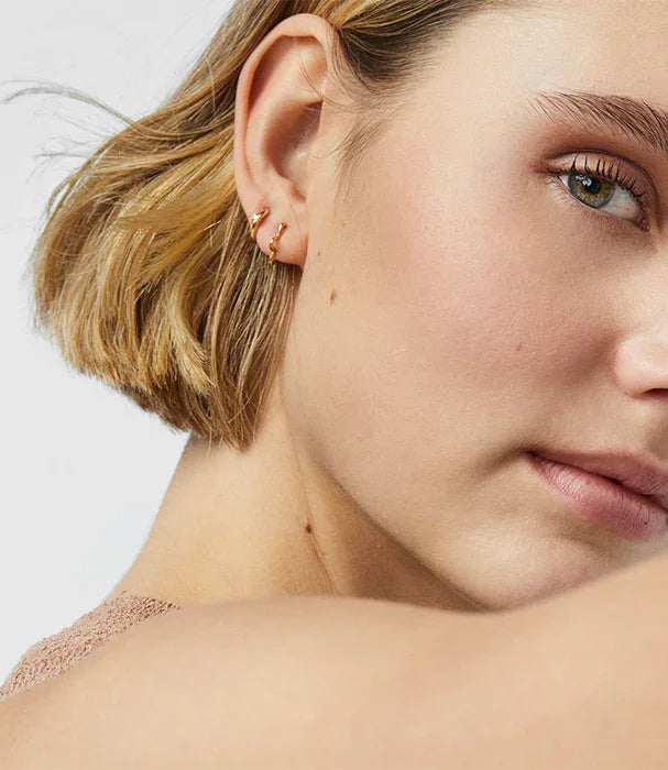 אישה עם שיער בלונדיני קצר עונדת עגילי זהב אופנתיים, תקריב מבית CHOZEN