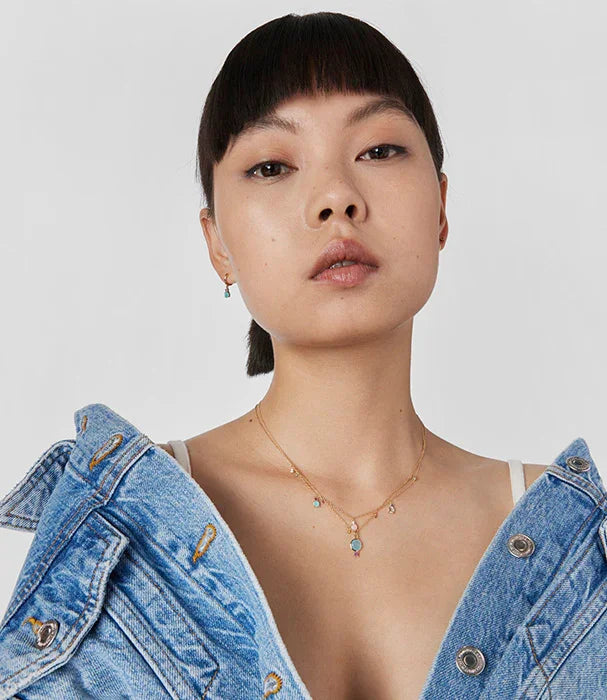 אישה עם ג'קט ג'ינס, עונדת שרשרת זהב ועגילים, אופנה טרנדית מבית CHOZEN