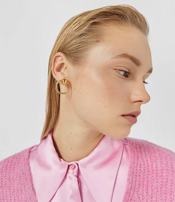 אישה עונדת עגיל זהב עגול, חולצה סאטן ורודה, מבט צד, CHOZEN מותגים מובילים