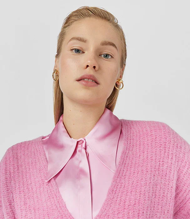 אישה עם חולצה ורודה מבריקה וסוודר ורוד, עגילי זהב, אופנה טרנדית מבית CHOZEN