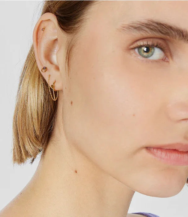 דוגמנית עם עגילים מוזהבים טרנדיים על רקע לבן מבית CHOZEN, מותגים מובילים בקבוצת אלפא