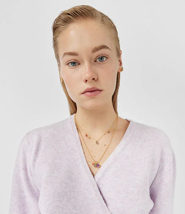 דוגמנית לובשת סוודר סגול בהיר, עונדת שרשראות זהב ועגילי זהב, צילום אופנה CHOZEN