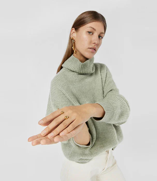 דוגמנית עם סוודר ירוק וטבעת זהב בעיצוב מודרני, משווקת באתר CHOZEN מותגים מובילים