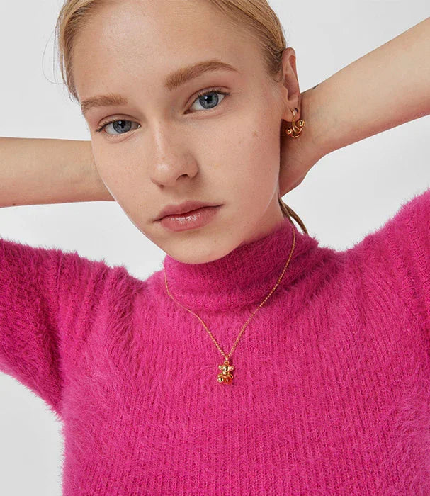 אישה עם סוודר ורוד, עונדת שרשרת ותכשיטים זהב, אופנה מבית CHOZEN