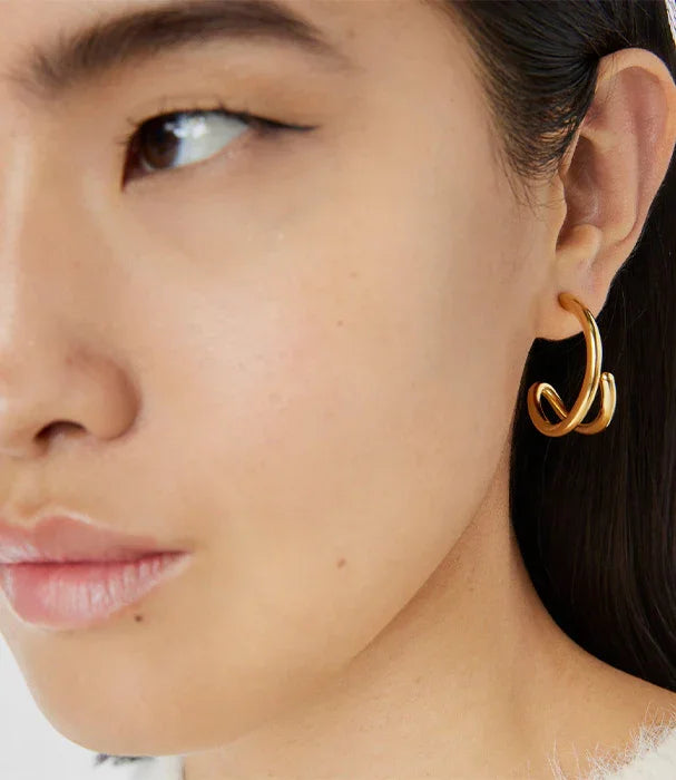 עגיל חישוק זהב מעוצב על אוזן של אישה, צילום תקריב, CHOZEN מותגים מובילים