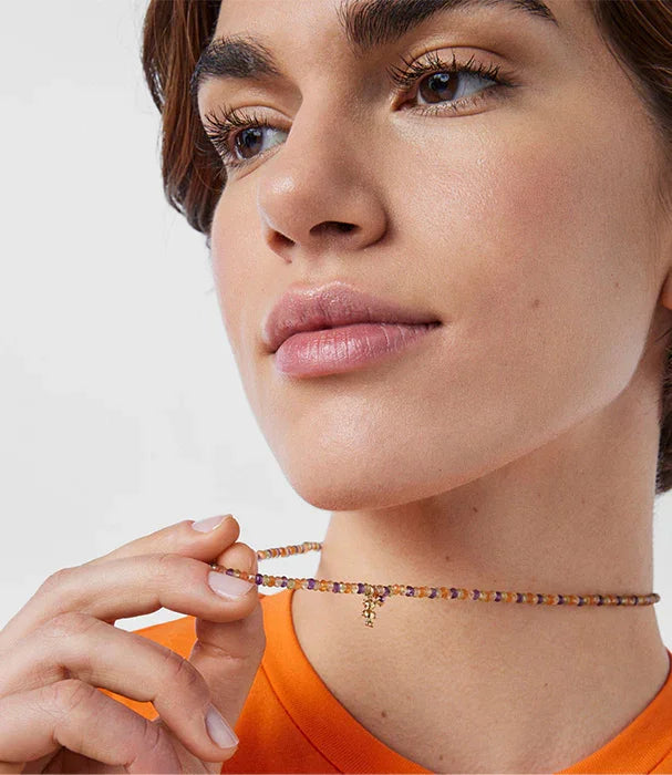 אישה צעירה לובשת שרשרת צבעונית עדינה עם תליון זהב, צילום תקריב לאתר CHOZEN