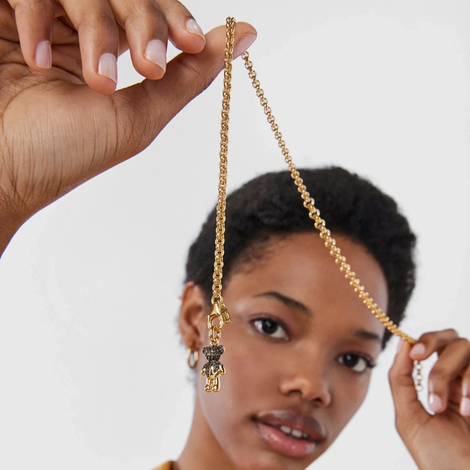 אישה מחזיקה שרשרת זהב עם תליון דובי, צילום תקריב, תכשיטי CHOZEN מבית קבוצת אלפא