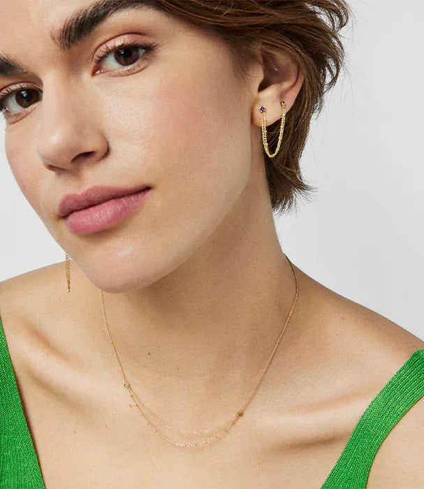 אישה עונדת עגילים ותכשיטי זהב אופנתיים, בחולצה ירוקה, צילום לקמפיין CHOZEN