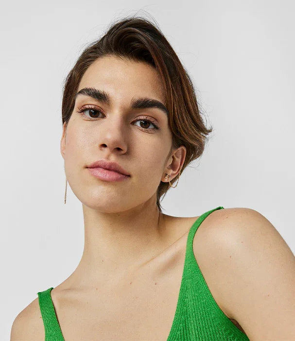 אישה עם שיער קצר עונדת עגילים ולובשת גופיה ירוקה, צילום אופנה לאתר CHOZEN