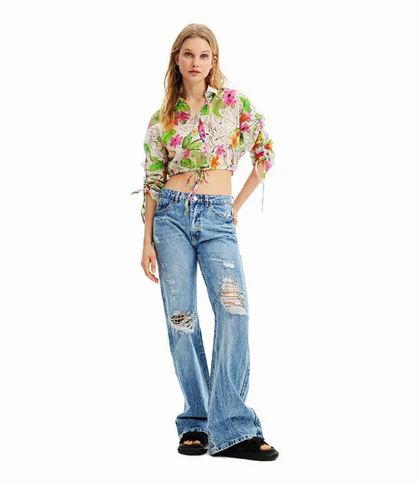 אישה לובשת חולצה פרחונית קצרה וג'ינס קרעים כחולים, אופנה טרנדית באתר CHOZEN
