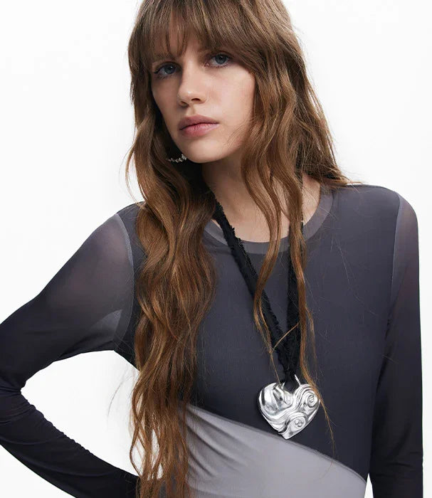 דוגמנית עם שיער גלי לובשת שמלה אפורה ותליון לב כסוף, צילום אופנה מותגי CHOZEN