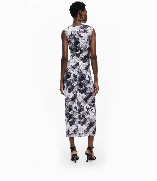 אישה בשמלת מקסי פרחונית שחור לבן עומדת על רקע לבן, אופנת CHOZEN