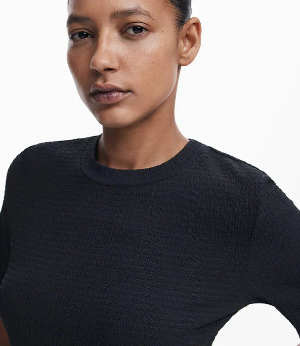 אישה לובשת חולצה שחורה מבית CHOZEN על רקע לבן, אופנת נשים יוקרתית