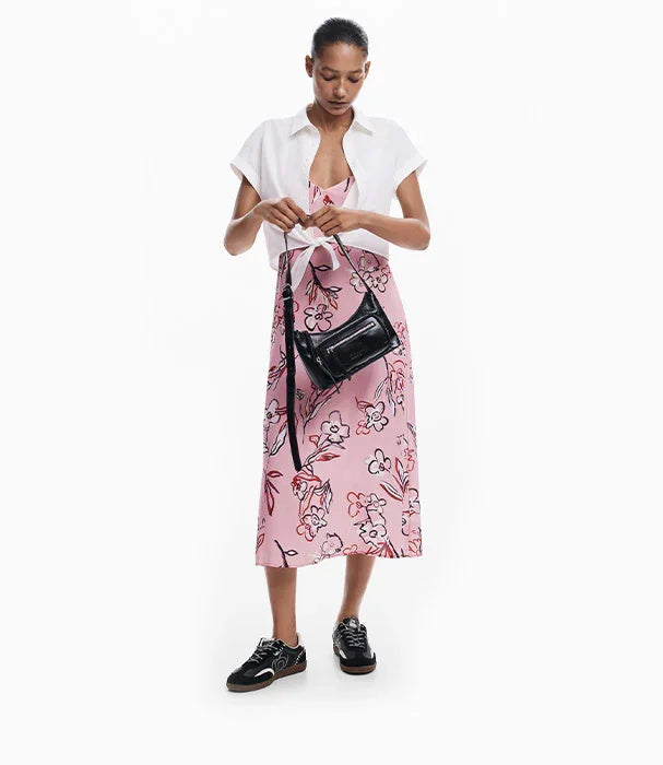 אישה בשמלת קיץ ורודה עם הדפס פרחים, סנדלי ספורט ותיק שחור, אופנה עדכנית מבית CHOZEN