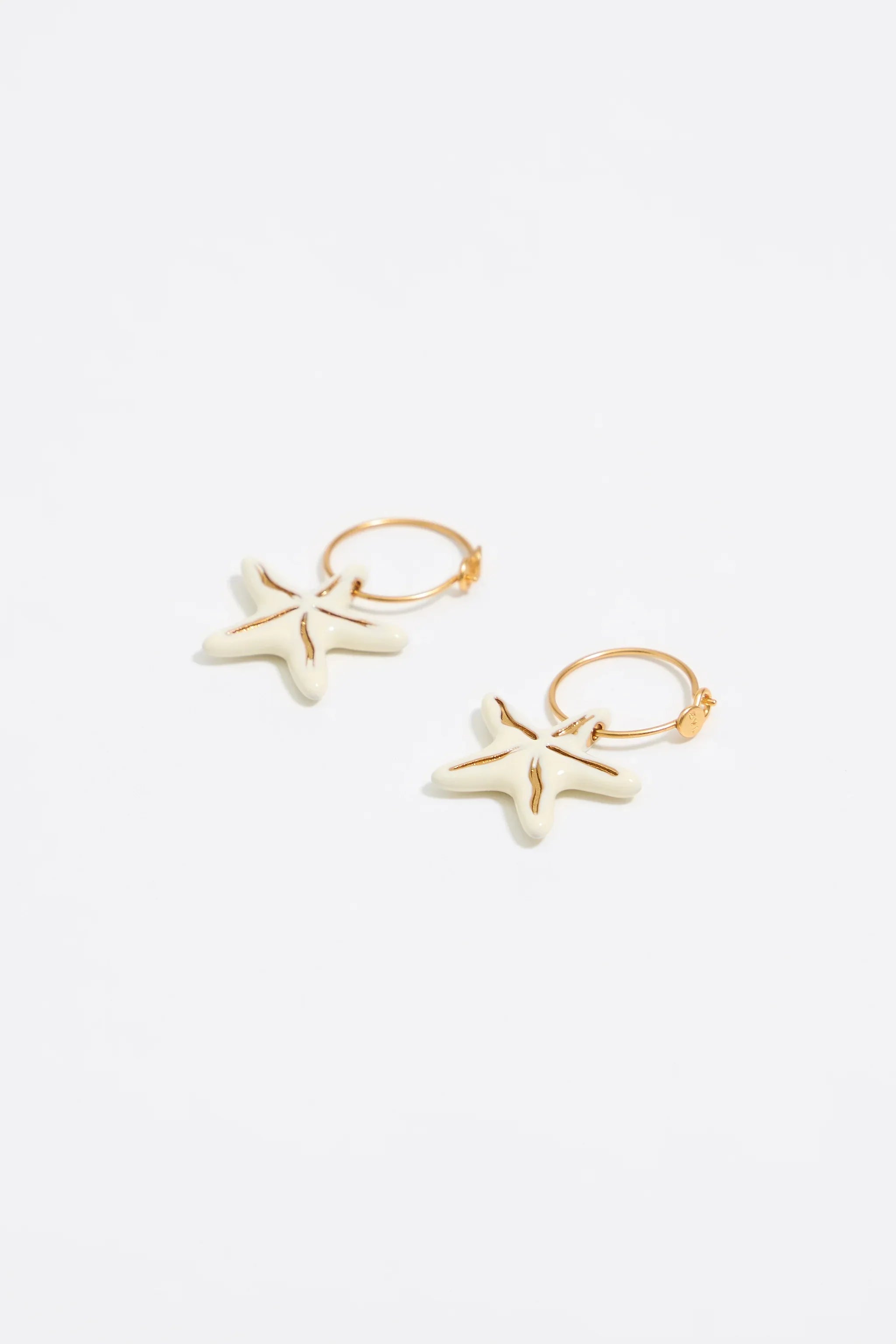 עגילי חישוק זהב בעיצוב כוכב ים מבית CHOZEN על רקע לבן