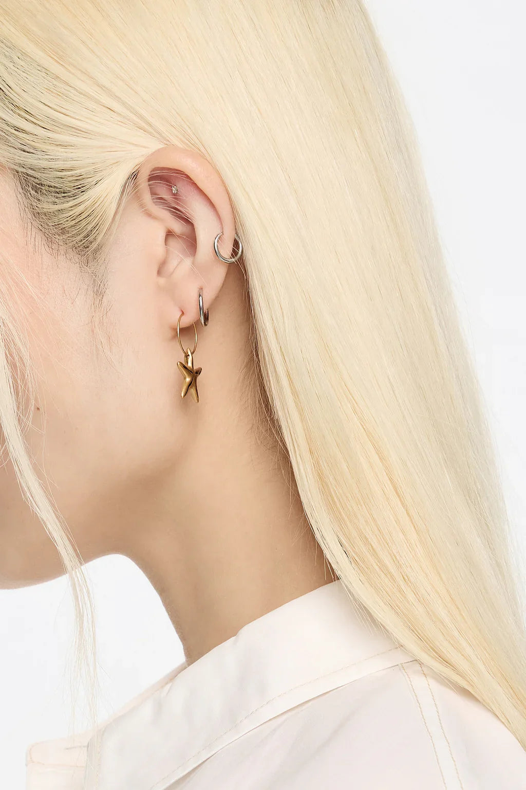 עגילי זהב בצורת כוכב ועגילי כסף על אוזן עם שיער בלונדיני, אופנה מבית CHOZEN