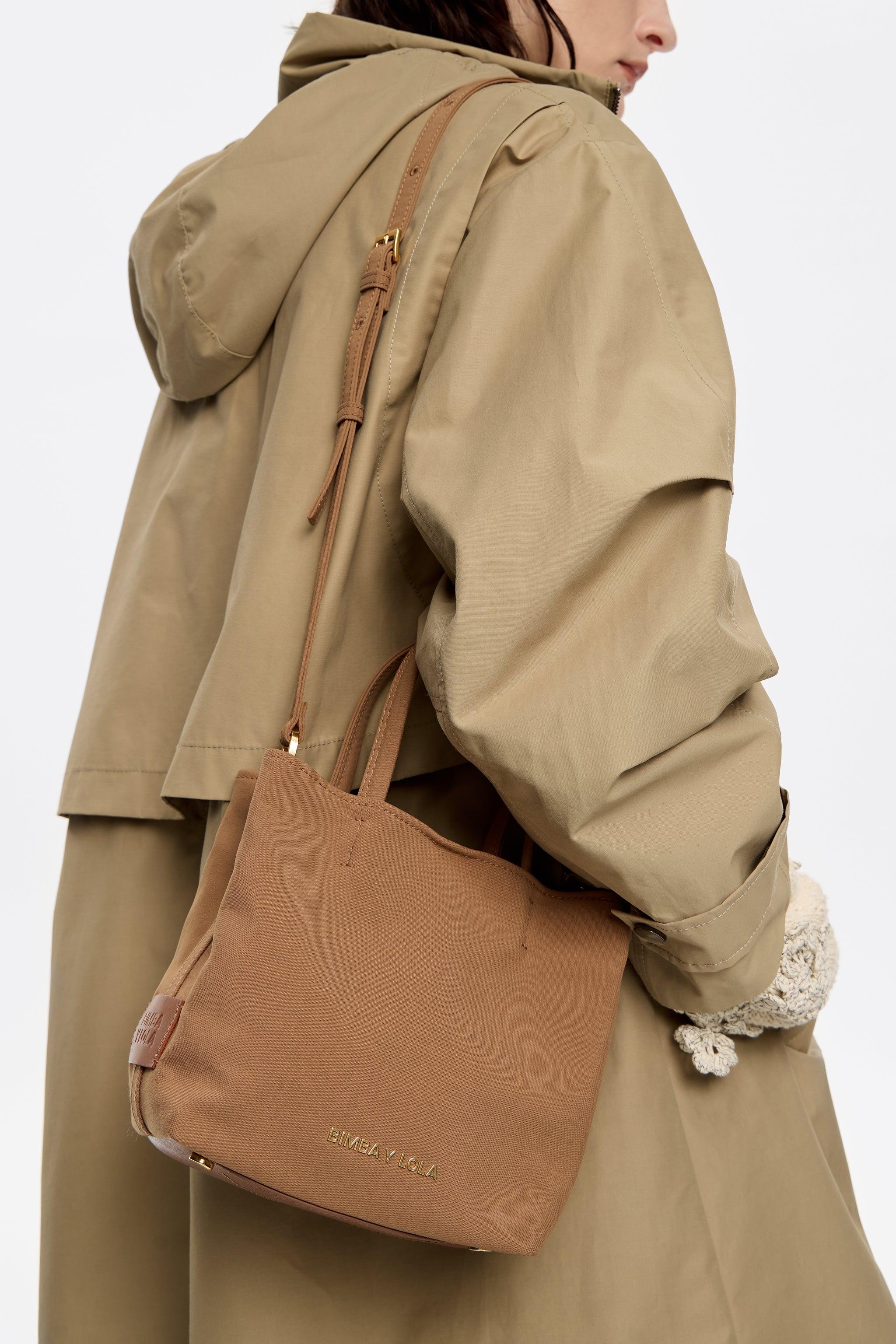 אישה עם מעיל בז', נושאת תיק צד חום של BIMBA Y LOLA, צילום אופנה CHOZEN