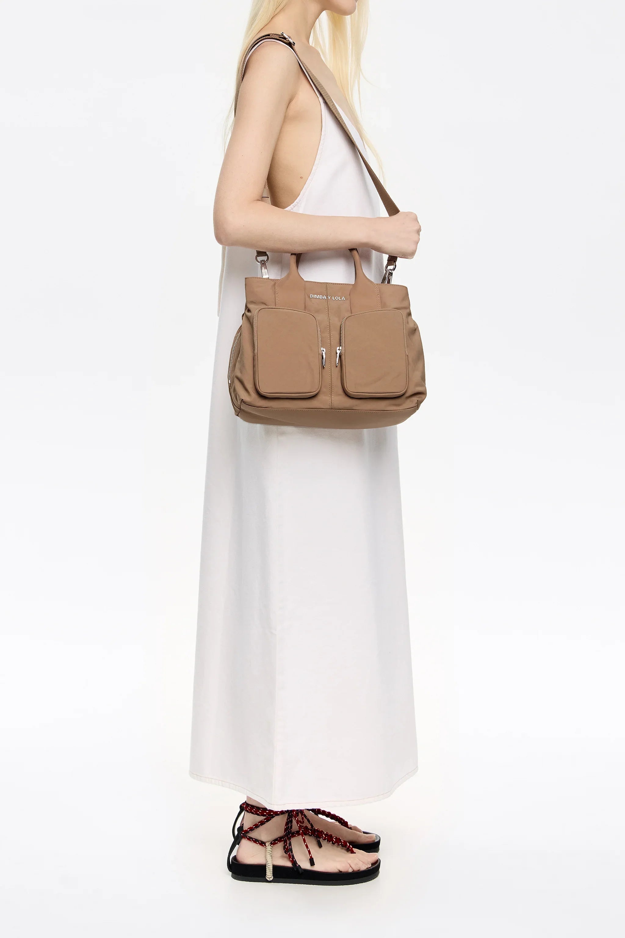 אישה בשמלה לבנה נושאת תיק בז' אופנתי Bimba Y Lola, צילום לאתר CHOZEN