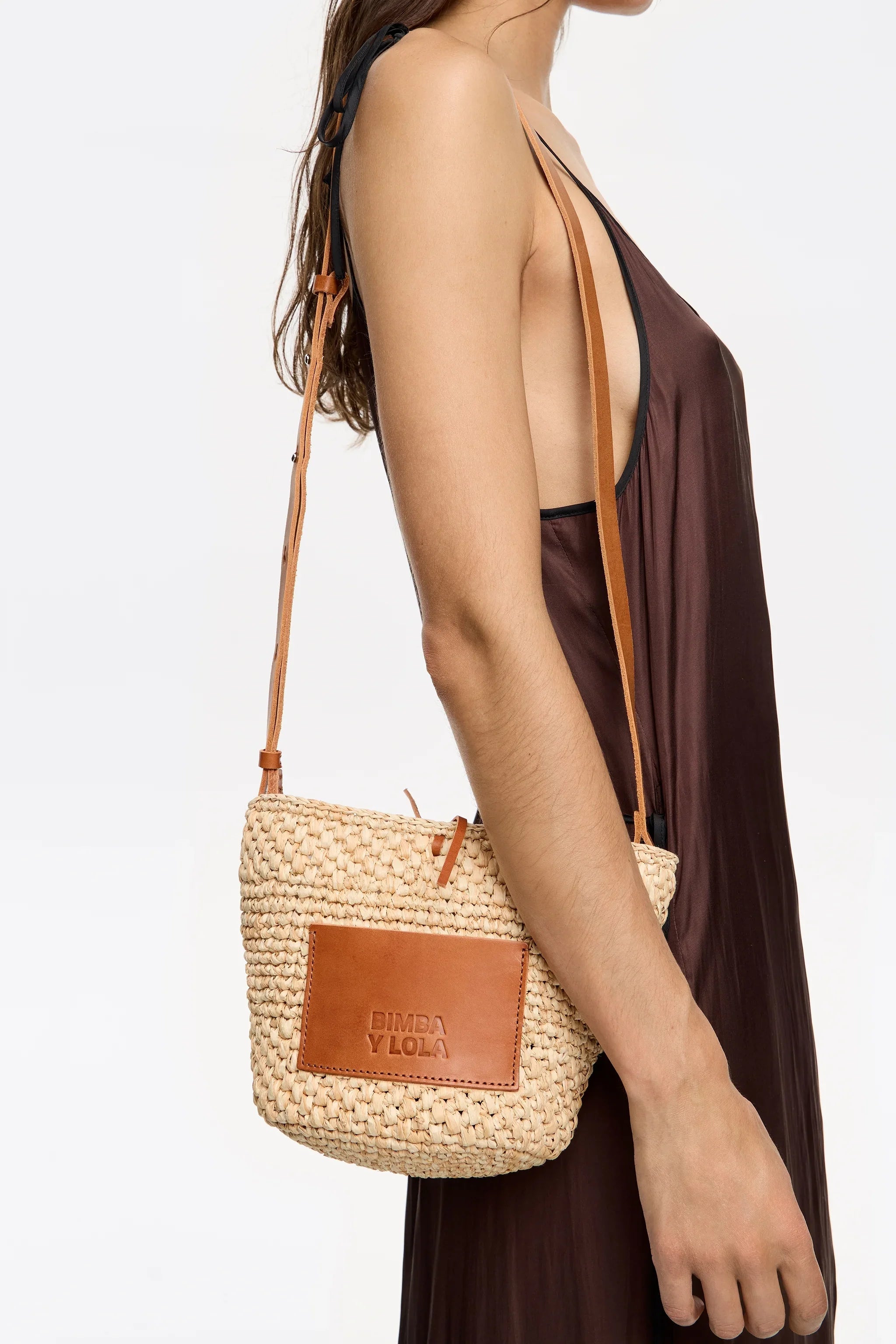 תיק צד קש עם רצועת עור חומה של BIMBA Y LOLA מבית CHOZEN, על דוגמנית בשמלה חומה