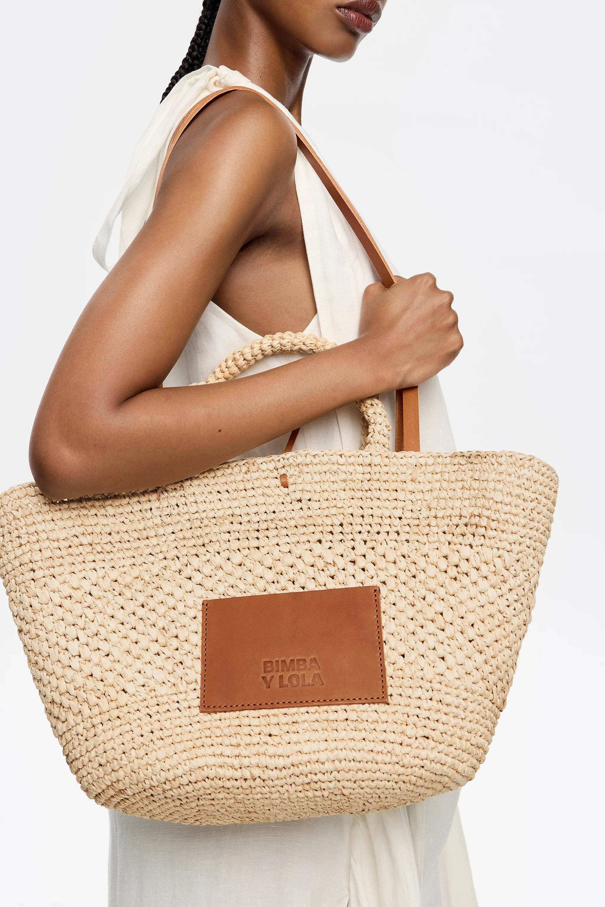 תיק קש אופנתי של BIMBA Y LOLA על אישה בלבוש קיץ, צילום לאתר CHOZEN מותגים מובילים