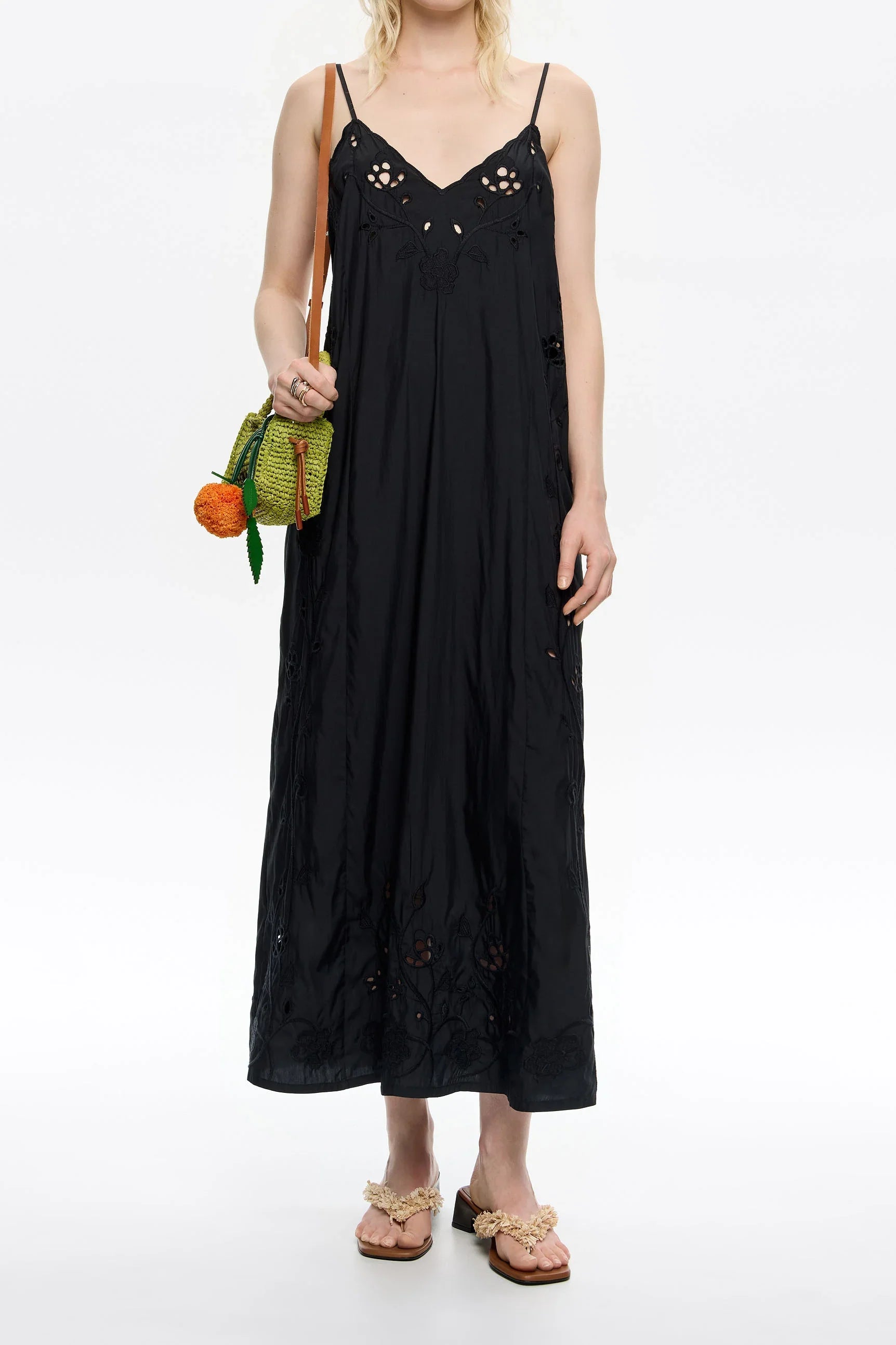 אישה בשמלת מקסי שחורה עם כתפיות דקות, תיק ירוק וסנדלים בעיצוב ייחודי, צילום אופנה ל-CHOZEN