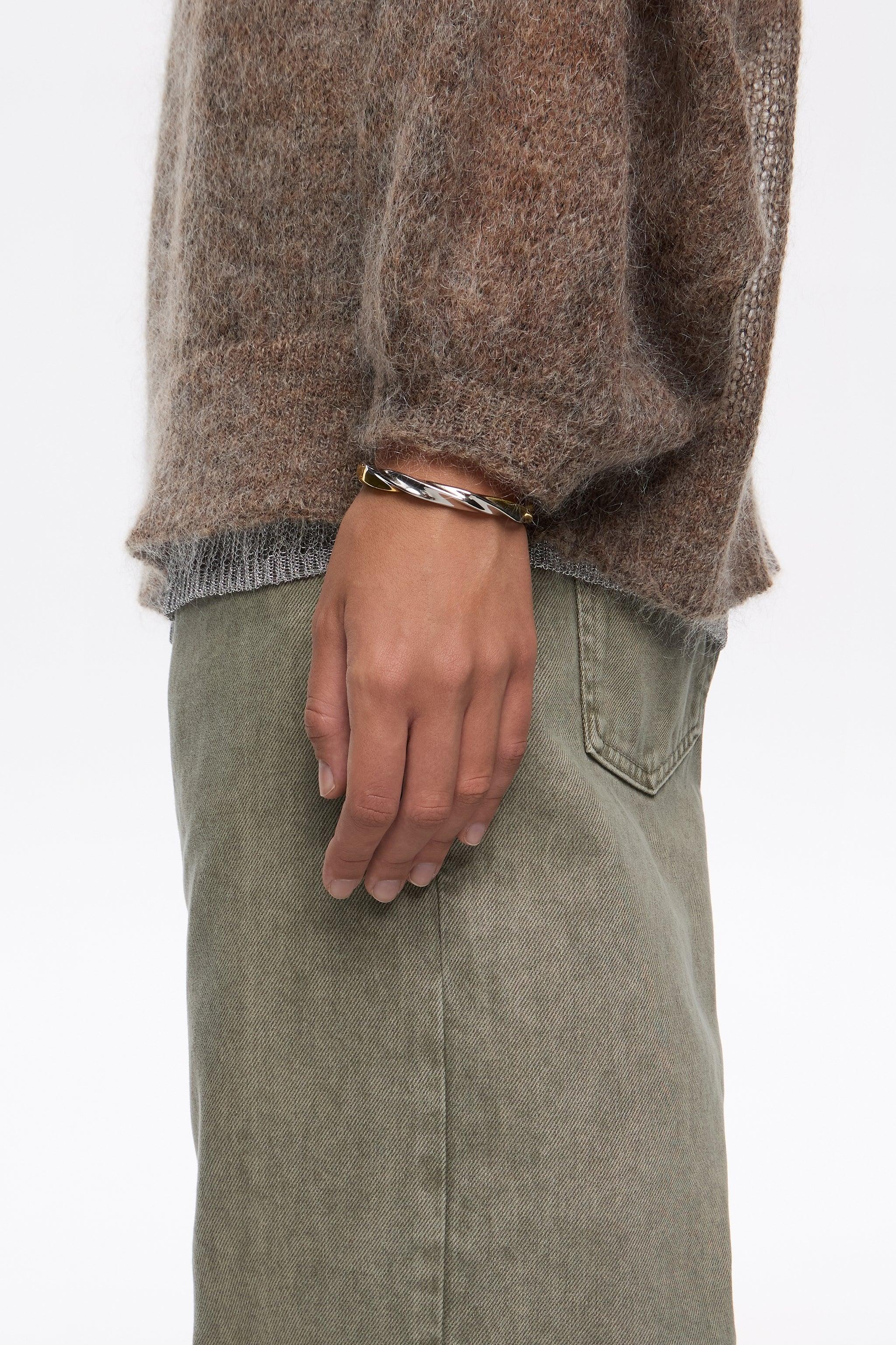 יד עם צמיד מתכת בעיצוב מודרני, סוודר חום ומכנס ירוק, אופנה CHOZEN מבית קבוצת אלפא